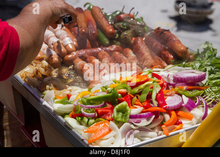 Street-food vendor-bacon cuisson enveloppé de hot dogs, oignons, poivrons et piments habanero durant Carnaval festival. Banque D'Images