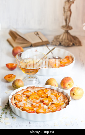 Le petit-déjeuner composé de Tarte aux abricots aux amandes, abricots frais et miel sur table en bois blanc Banque D'Images