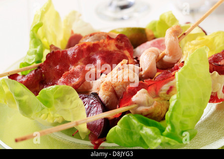 Les brochettes de poulet et de bacon servi sur des feuilles de laitue Banque D'Images