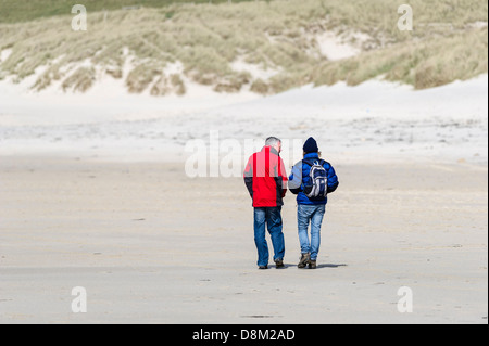 Deux personnes marchant le long de la plage de Sennen Cove à Cornwall. Banque D'Images