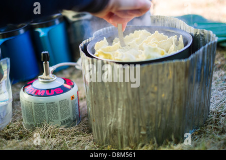 La cuisson des pâtes sur une petite cuisinière en camping sauvage dans une tente. Banque D'Images