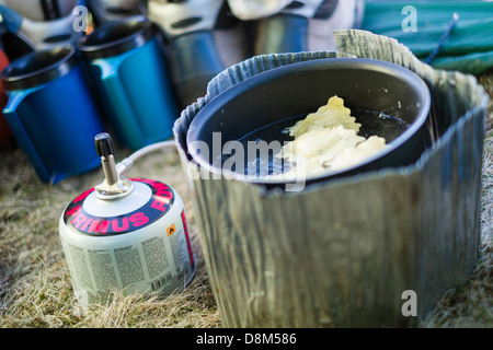 La cuisson des pâtes sur une petite cuisinière en camping sauvage dans une tente. Banque D'Images