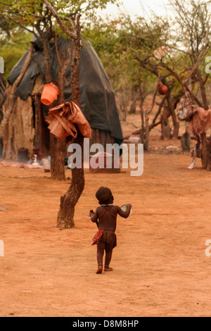 Un enfant marcher autour de leur village Himba. Banque D'Images