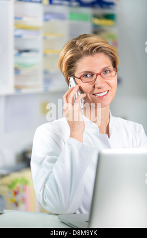 Jeune femme médecin avec ordinateur portable et téléphone mobile Banque D'Images