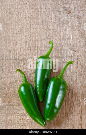 Piments Jalapeno - trois piments Jalapeno sur une planche ou un fond rustique. Banque D'Images