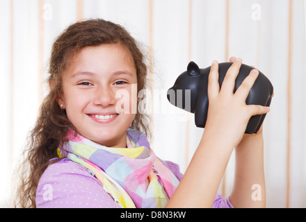 Petite fille d'économiser de l'argent dans une tirelire Banque D'Images