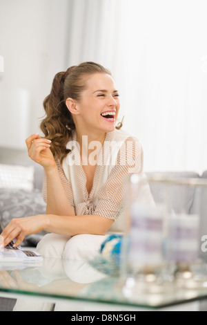 Souriante jeune femme assise sur le divan dans la salle de séjour Banque D'Images