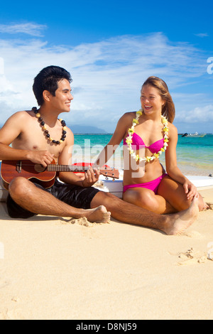 Couple sur la plage avec leurs skis surf jouer ukulele Banque D'Images