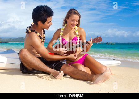 Couple sur la plage avec leurs skis surf jouer ukulele Banque D'Images