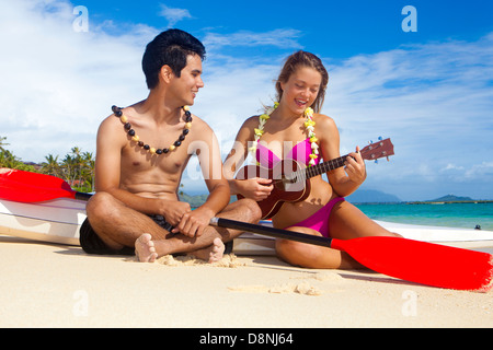 Couple sur la plage avec leurs skis surf jouer ukulele Banque D'Images