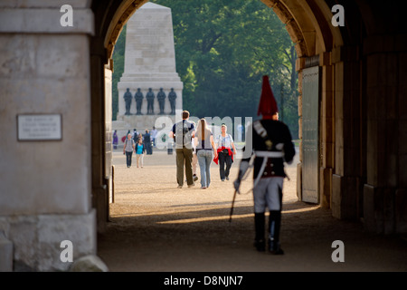 Un couple marche à travers Horse Guards Parade, Londres, Royaume-Uni, avec une garde à cheval en uniforme au premier plan. Banque D'Images