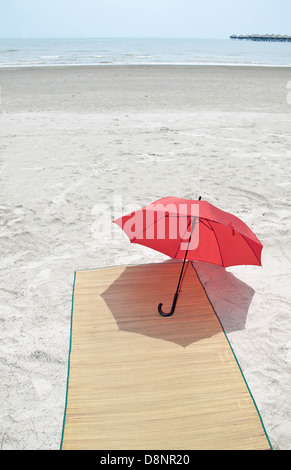 Parapluie rouge et bambou sur la plage Banque D'Images
