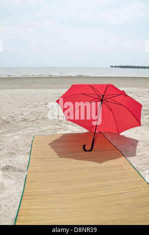 Parapluie rouge et bambou sur la plage Banque D'Images