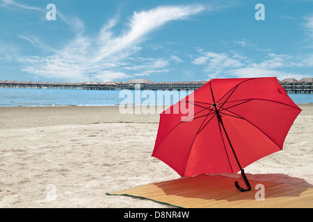 Parapluie rouge et bambou sur la plage Banque D'Images