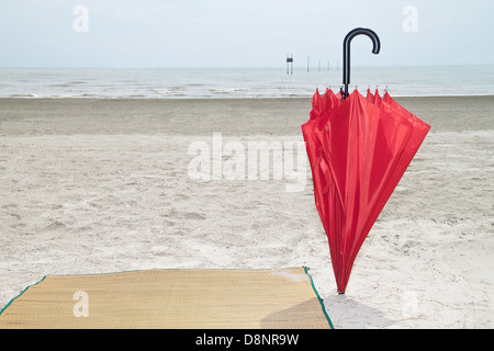Parapluie rouge et bambou sur la plage Banque D'Images