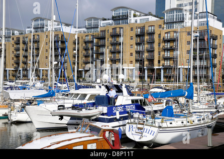 Homme debout sur un bateau à St Katharine Docks, avec vue sur la marina et donnant sur modern appartements / appartements. Londres, Angleterre, Royaume-Uni. Banque D'Images