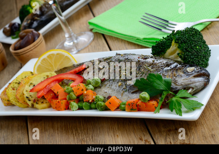 Truite au four avec un plat et des légumes sur la table de cuisine Banque D'Images