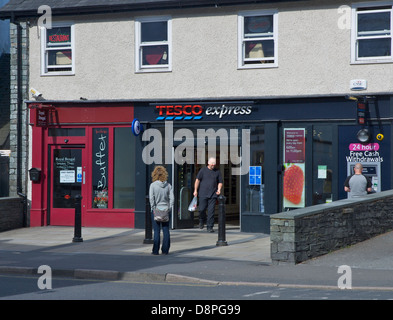 Homme marchant hors de la Tesco Express store à Ambleside, Parc National de Lake District, Cumbria, Angleterre, Royaume-Uni Banque D'Images