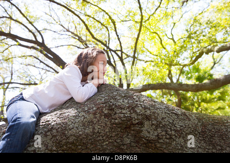 Beaux enfants kid girl resting allongé sur une branche d'arbre Banque D'Images