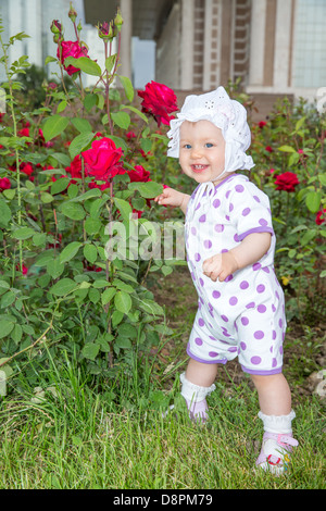 Smiling jolie petite enfant fille avec fleur rose in park Banque D'Images