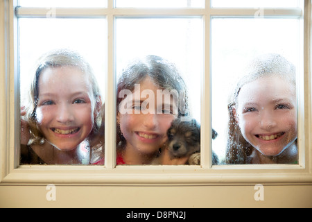 Trois amis soeur regardant par la fenêtre avec un chiot et de gouttes Banque D'Images