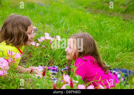 Heureux soeur jumelle de jeunes filles, jouant sur les fleurs de printemps meadow Banque D'Images