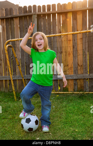 Petite fille blonde joueur de football professionnels en cour avec ball Banque D'Images