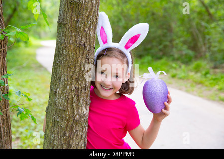 Fille de pâques avec de grands oeufs mauve et funny Bunny Ears sur la forêt Banque D'Images