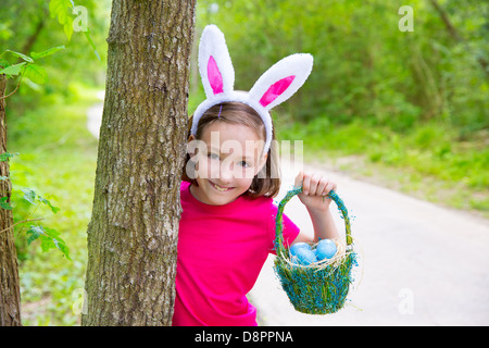 Fille avec des oeufs de pâques panier et funny bunny expression face à la forêt Banque D'Images