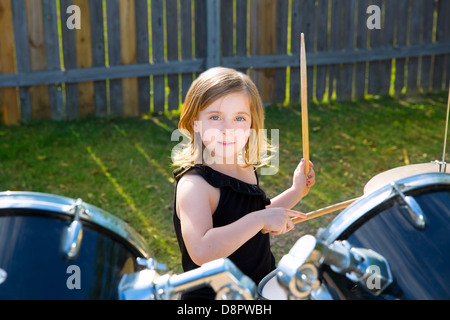 Kid girl blonde batteur jouant des percussions à tha pelouse arrière Banque D'Images