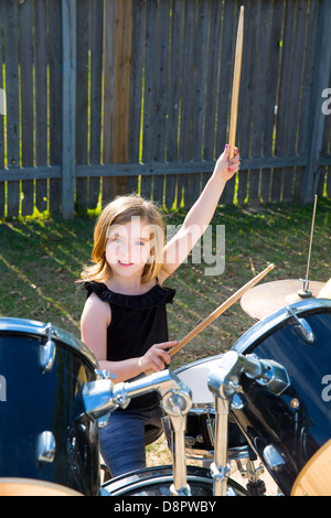 Kid girl blonde batteur jouant des percussions à tha pelouse arrière Banque D'Images