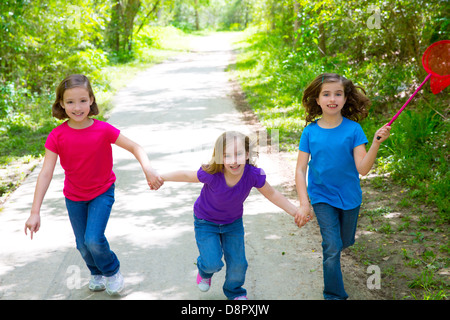 Les amis et ma soeur filles exécutant dans la piste en forêt smiling happy avec butterfly net Banque D'Images