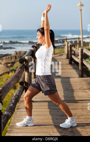 Mettre en place le milieu de l'âge femme faisant des exercices matinaux sur la plage Banque D'Images