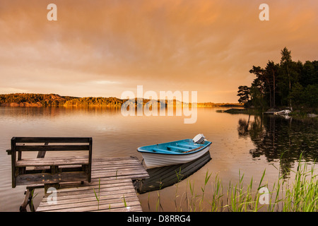 Petit bateau amarré à une jetée sur un lac en Suède, soir Banque D'Images