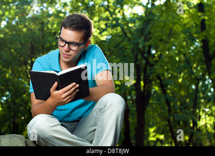 Young man reading book in the park Banque D'Images