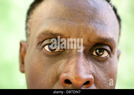 Les personnes âgées et les émotions, portrait de senior african american man looking at camera contre mur vert Banque D'Images