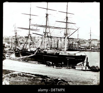 Cette photographie en noir et blanc de 1871 représente Circular Quay à Sydney, en Nouvelle-Galles du Sud. L'image montre le front de mer animé avec des bateaux et des charrettes tirées par des chevaux, offrant un aperçu de la vie quotidienne dans la région à la fin du XIXe siècle. Circular Quay était une plaque tournante pour les transports et le commerce à Sydney, ce qui en fait un élément emblématique de l'histoire de la ville. Banque D'Images