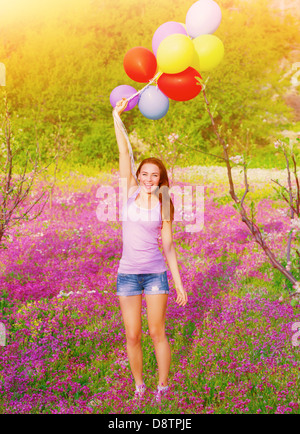 Happy young woman holding en mains plusieurs ballons colorés, s'amusant sur dentelle et terrain, l'heure d'été saison Banque D'Images