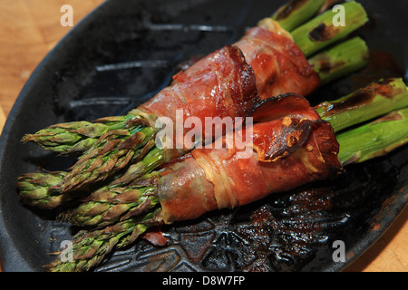 Asperges rôties enveloppées dans le jambon sur un poêle en fonte Banque D'Images