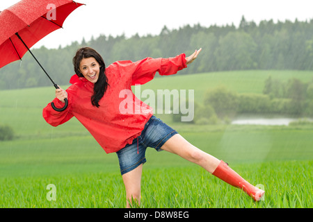 Happy girl ludique sous la pluie avec parapluie rouge Banque D'Images