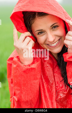 Portrait of smiling adolescent dans la pluie en imperméable rouge Banque D'Images