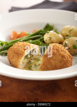 Poulet à la kiev ouvert suintant libérant le beurre chaud les haricots verts Carottes Pommes de terre aux herbes Banque D'Images