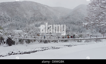 Le passage touristique pont suspendu couvert de neige à Shirakawago Ogimachi dans une froide journée d'hiver Banque D'Images