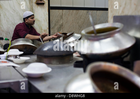 Un homme sert de curries pots énormes dans la cour à Karims Restaurant, Old Delhi Banque D'Images