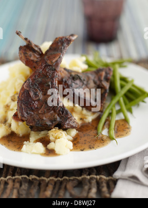 Côtelettes d'agneau pommes de terre purée de haricots sauce de viande au dîner Banque D'Images