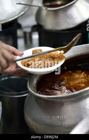 Un homme sert de curries pots énormes dans la cour à Karims Restaurant, Old Delhi Banque D'Images