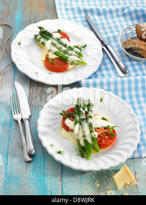 Les asperges vertes et les tomates avec crème de parmesan et d'origan Banque D'Images