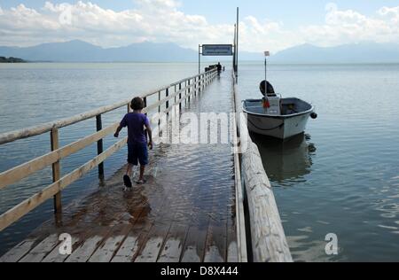 Grabenstätt, Allemagne. 5 juin, 2013. Un garçon marche sur une jetée couvertes par l'eau au Chiemsee à Grabenstätt, Allemagne, 05 juin 2013. Photo : Andreas GEBERT/dpa/Alamy Live News Banque D'Images