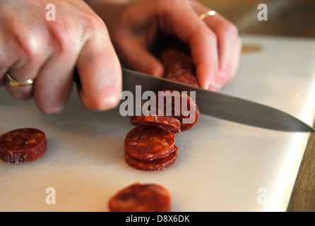 Close up d'un couteau couper des tranches de chorizo espagnol Banque D'Images