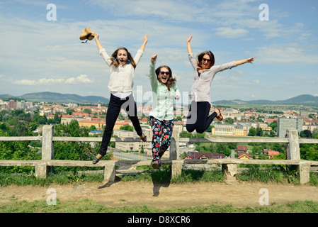 Trois jeunes femmes saut, avec un panorama de la ville derrière eux Banque D'Images